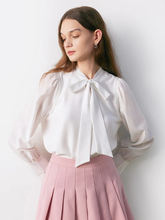 a lady in white bow blouse with pink skirt